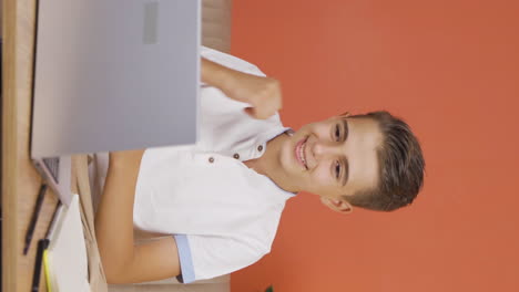 Vertical-video-of-Successful-boy-sees-good-results-on-laptop.